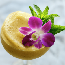 Frozen cocktail topped with a fresh purple orchid flower and mint garnish – edible floral decoration for upscale drinks