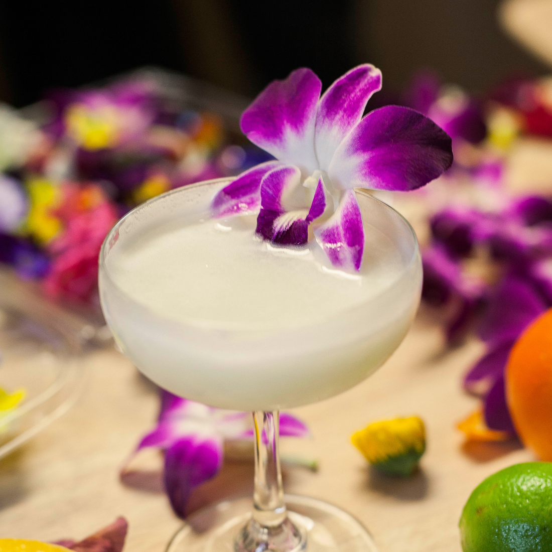 Frozen cocktail topped with a fresh purple orchid flower and mint garnish – edible floral decoration for upscale drinks