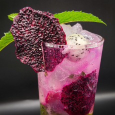 Pink tropical cocktail garnished with dried red dragon fruit and mint leaf – tiki bar drink styling