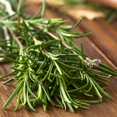 Fresh sprigs of rosemary on a wooden surface, ideal for use as cocktail garnish, culinary herb, or aromatic ingredient in mixology and cooking