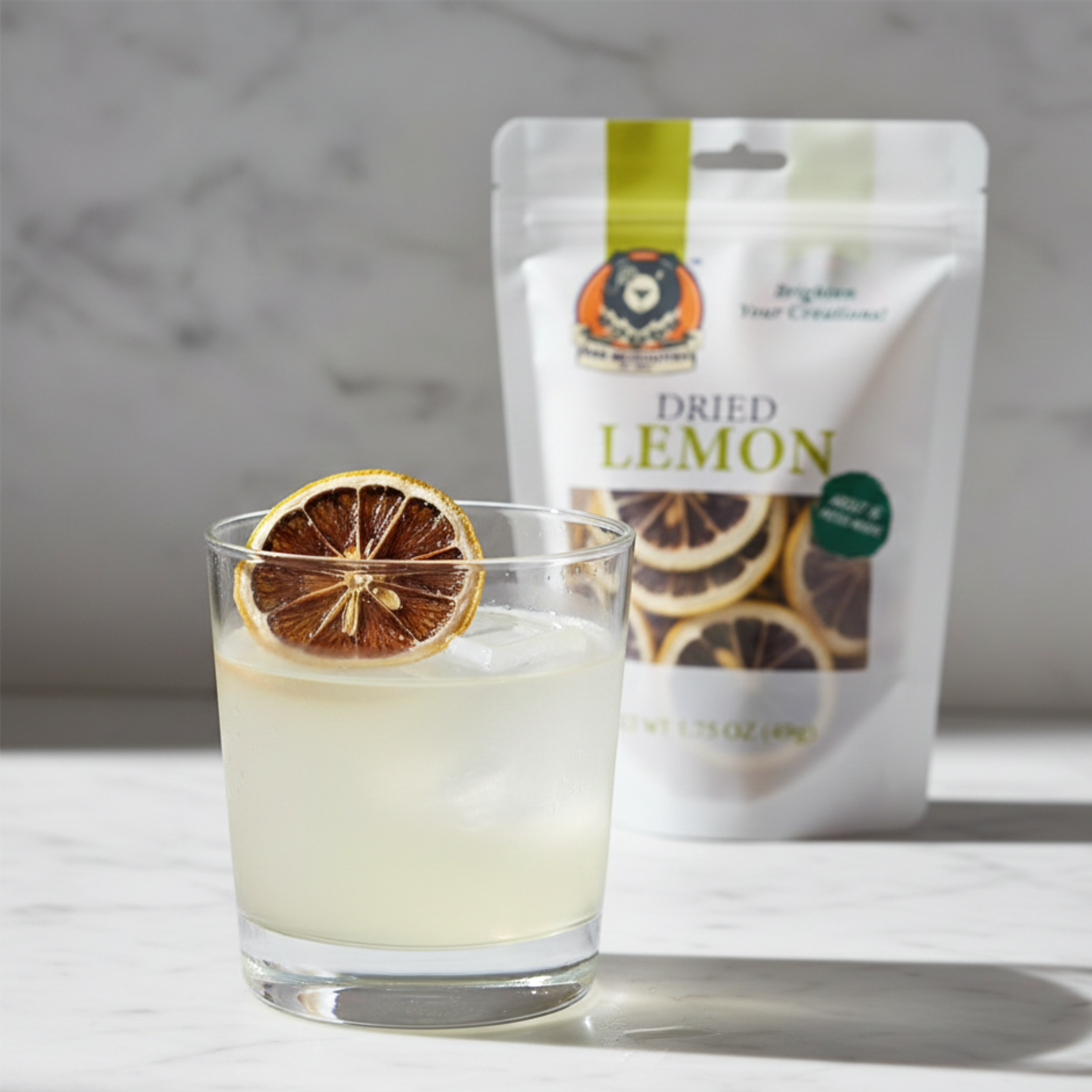 Glass of lemonade with a dried lemon slice and a package of dried lemons on a marble surface.