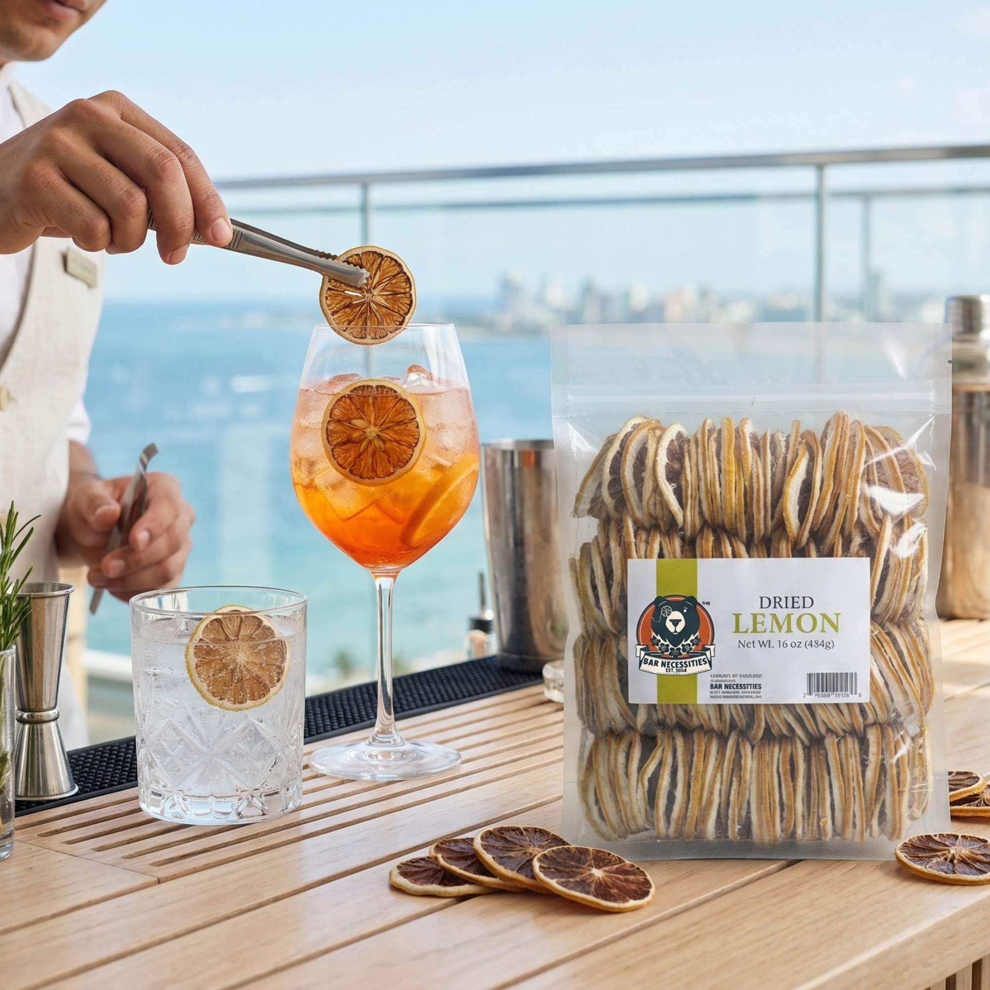 Person garnishing a cocktail with dried lemon slices, next to a package of dried lemon sticks and a glass of lemonade.