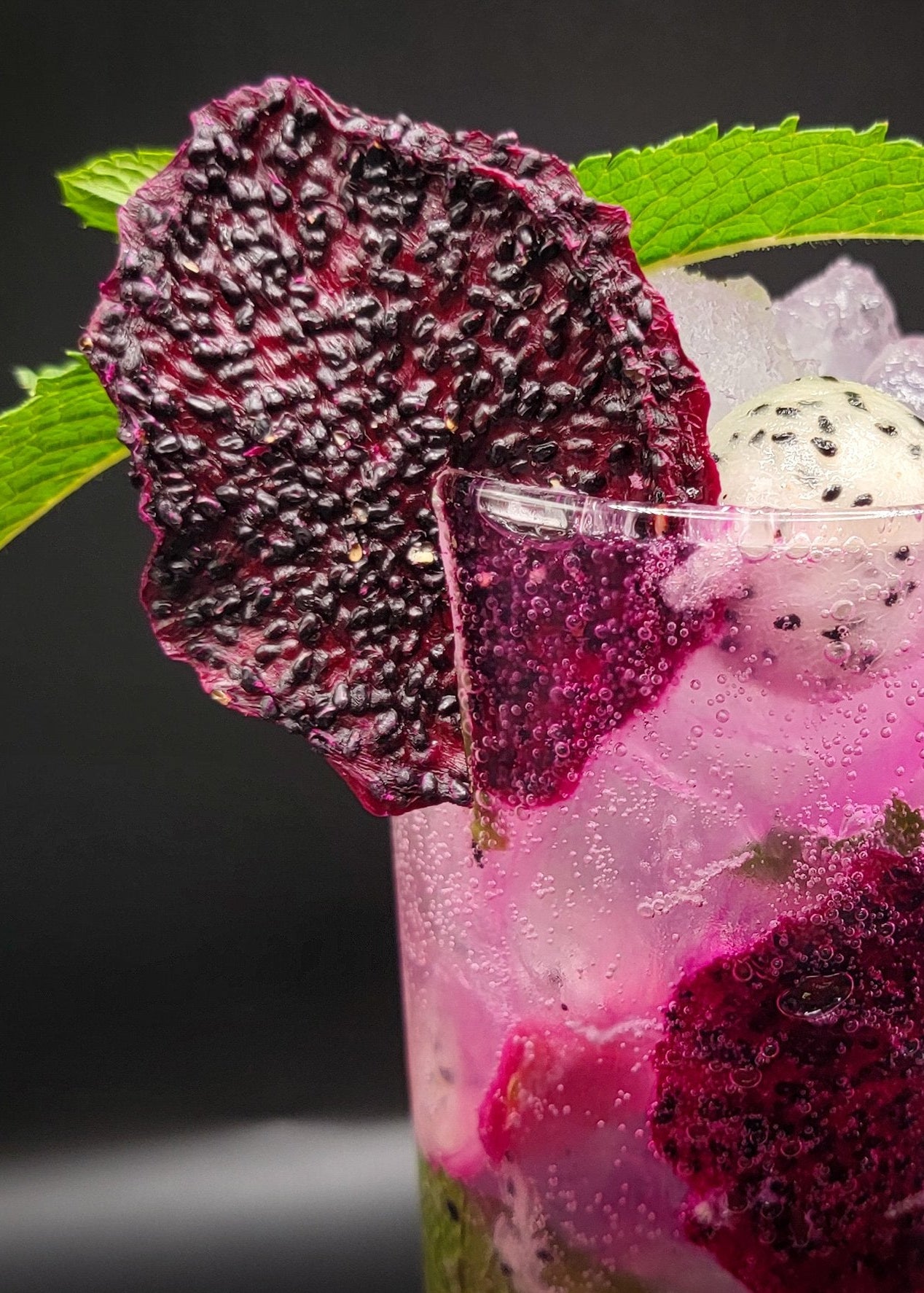Vibrant cocktail with dragon fruit chips and mint — exotic dehydrated fruit garnish for mixology and event cocktails