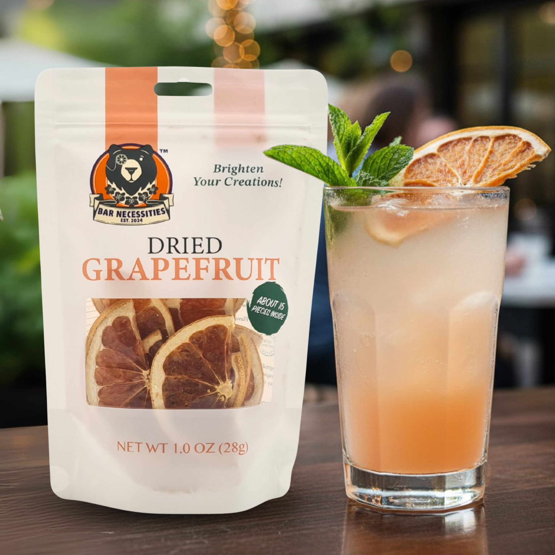 Dried grapefruit package next to a cocktail with grapefruit slices and mint leaves.