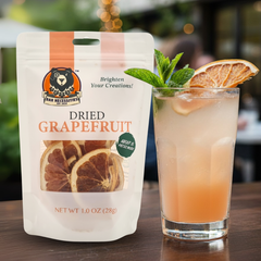 Dried grapefruit package next to a cocktail with grapefruit slices and mint leaves.