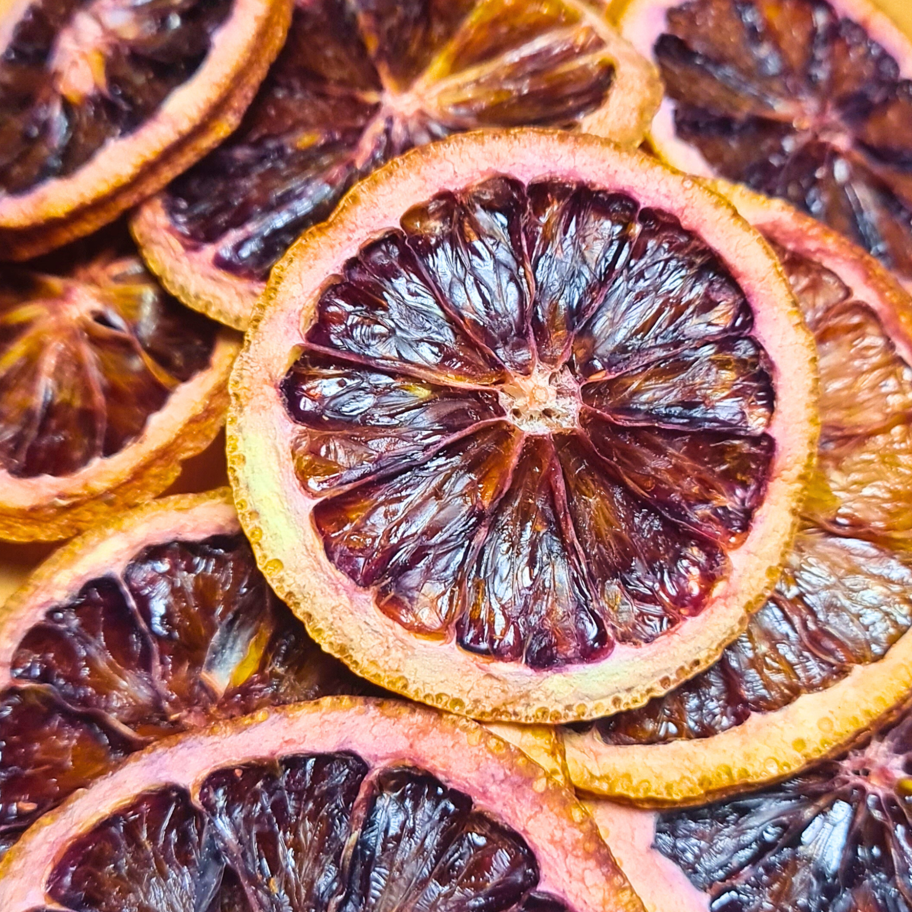 Close-up of dried blood orange wheels with deep red centers and citrus rind, ideal for cocktails, upscale food plating, and gourmet gift boxes.